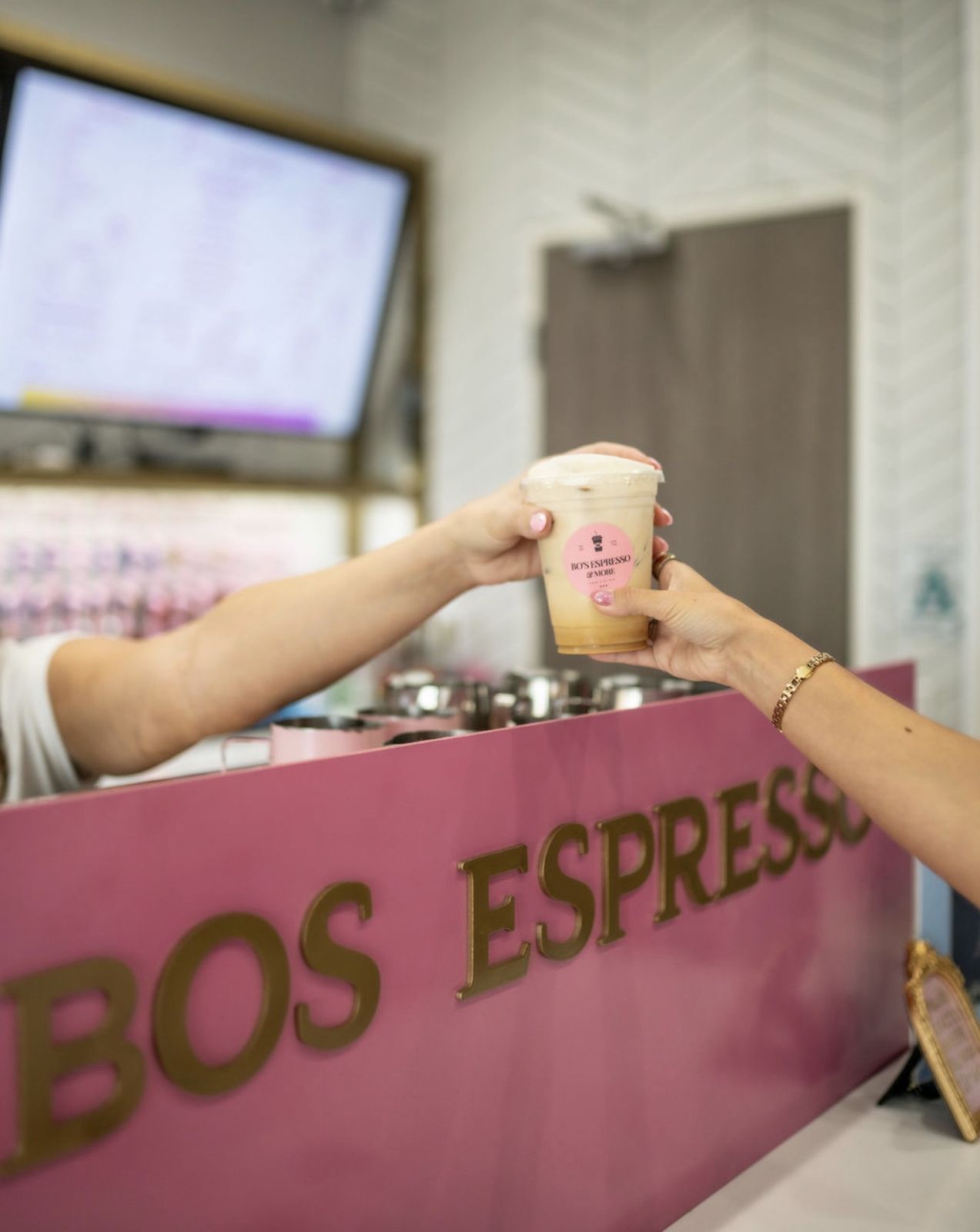 Hands passing a Bo's Espresso cup over the counter
